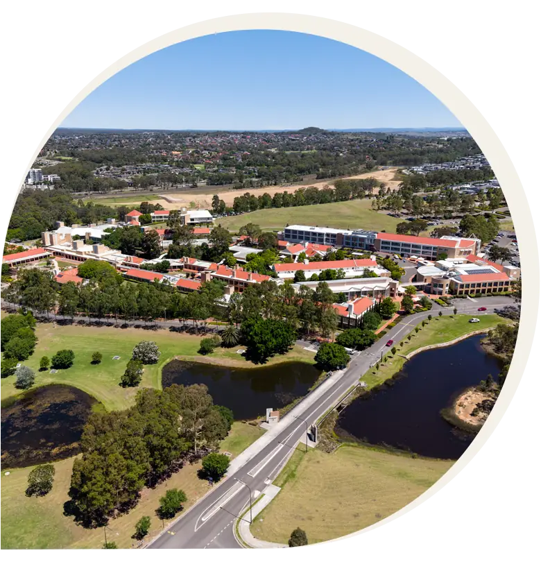 Aerial view of a campus with red-roofed buildings, green lawns, trees, ponds, and a road crossing through the landscape on a clear day—reminiscent of the picturesque settings being considered for Campbelltown land for sale.