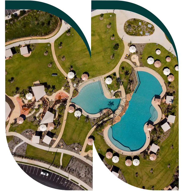 Aerial view of a landscaped park with two large pools, shaded seating areas, paths, grassy lawns, and a surrounding car park—seen through a geometric overlay—highlights the tranquil centrepiece of this new land development featuring premium plots.
