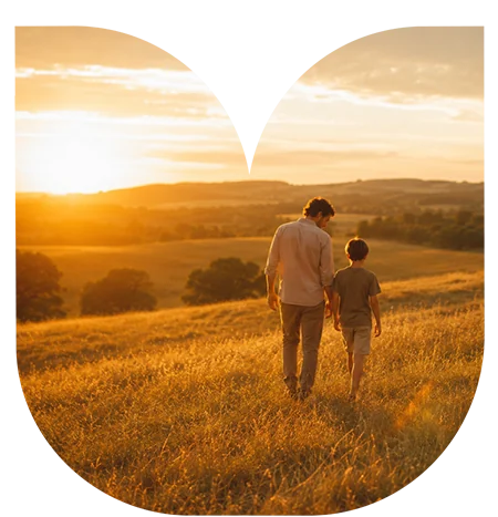 An adult and a child walk through a grassy field at sunset, surrounded by rolling hills and trees, framed by a white graphic shape—capturing the promise of new land development in this picturesque setting.